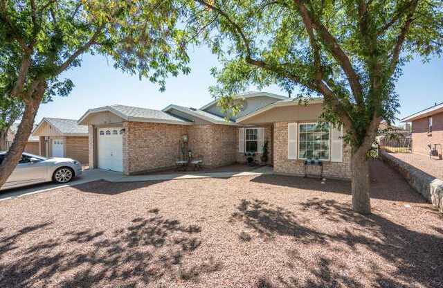 A house with a driveway and a tree in front.
