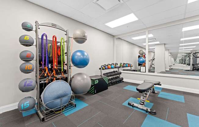 A gym with a variety of equipment including a weight rack, exercise balls, and a bench press.
