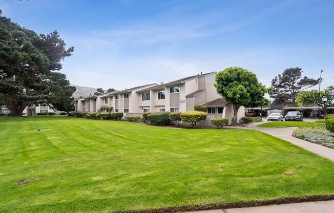 A row of houses with green lawns in front.