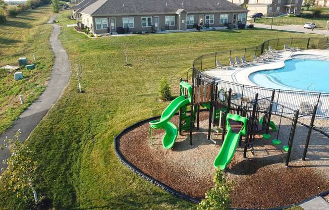 a playground with slides and a pool in front of a house