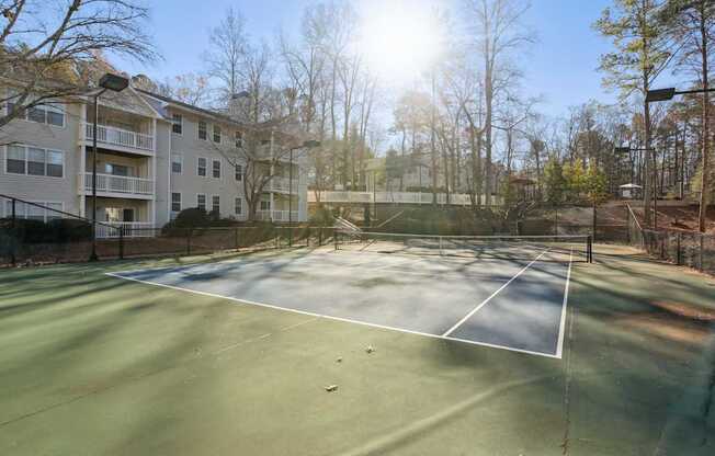 A tennis court is surrounded by apartment buildings.