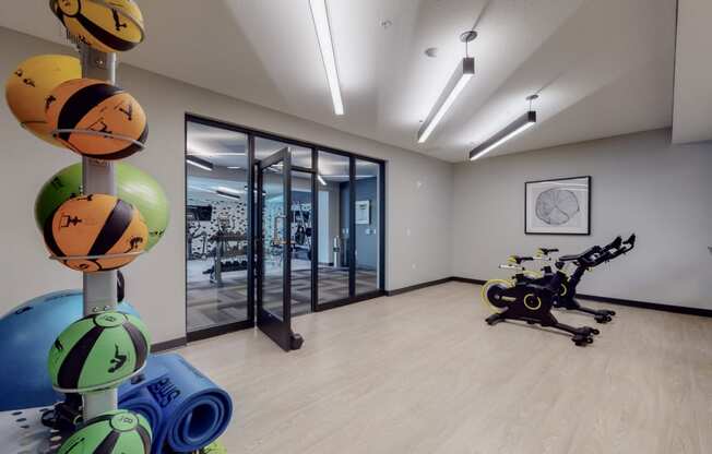 a gym with a bike and weights in the foreground and a glass door in the background