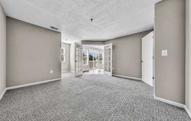 an empty living room and hallway with doors to a patio