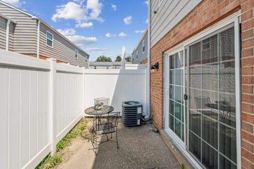 A patio with a table and chairs is surrounded by a white fence at Staples Mill Townhomes Apartments, Richmond, VA
