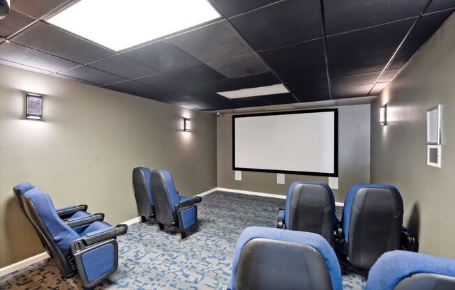 a screening room with blue chairs and a projector screen