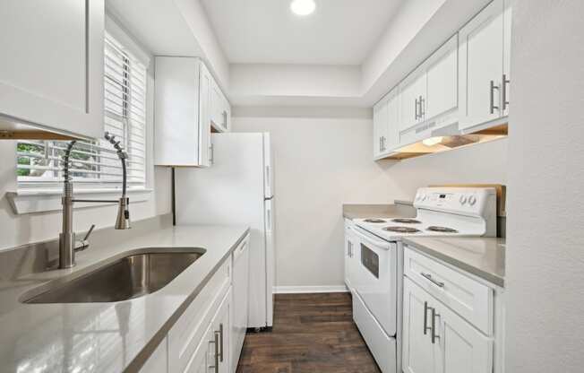 a white kitchen with white appliances and white cabinets at Woodlands of Plano in Plano, TX