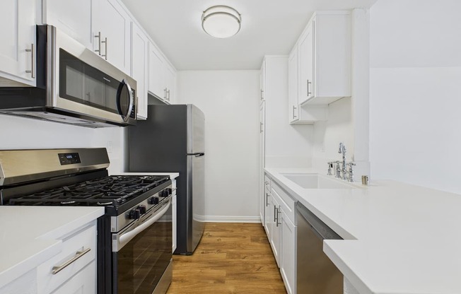 A kitchen with black and white appliances and wooden floors.