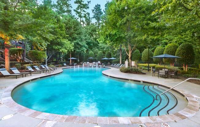 a resort style pool with lounge chairs and umbrellas