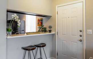 a bar with two stools in a kitchen with a white door