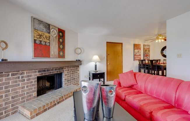 Living room in the one-bedroom model unit at Olde English Village, featuring a stone-brick fireplace and cozy seating.