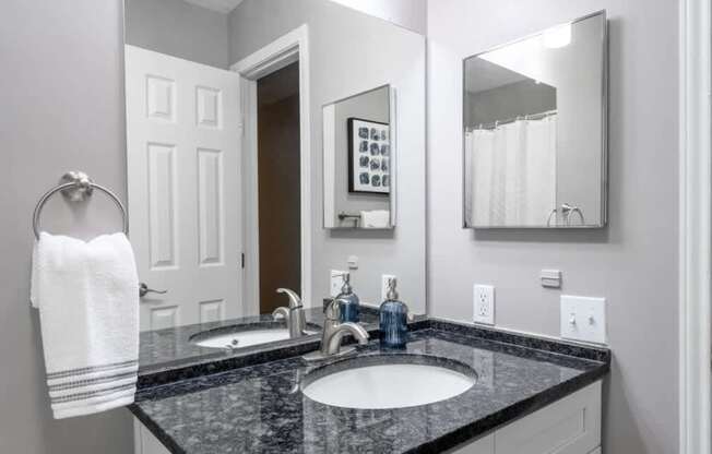 A bathroom with a black granite countertop and a white towel hanging on the towel rack.