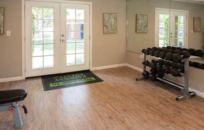 a fitness room with weights and a yoga mat on the hardwood floor