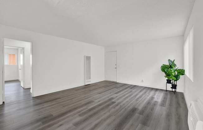 an empty living room with white walls and wood floors
