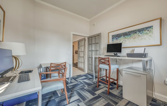 A room with a desk, chair, and a framed picture on the wall.