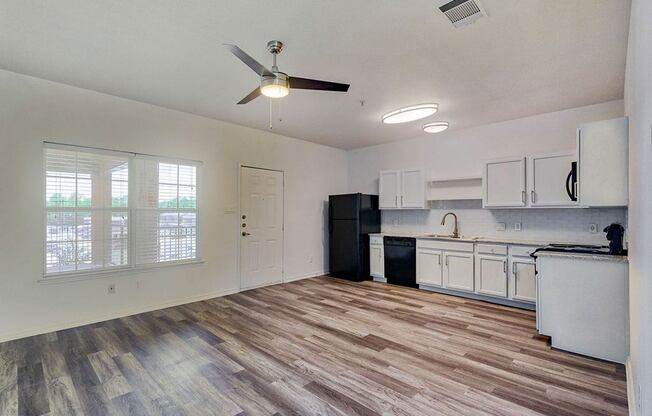 an empty kitchen and living room with a ceiling fan