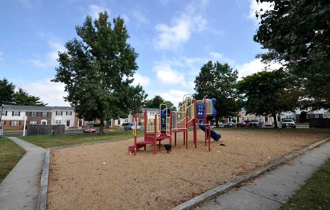 A playground with a red swing set and a blue slide.