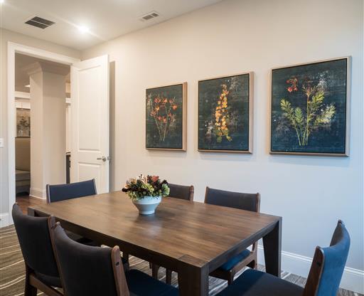 A cozy dining space with floral artwork and a wooden table surrounded by chairs.