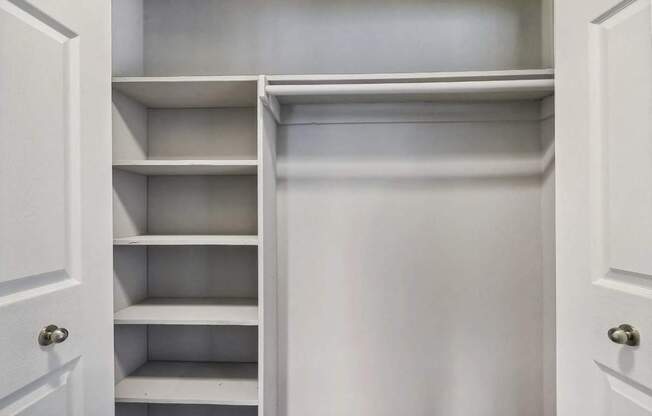 A white closet with shelves and doors.