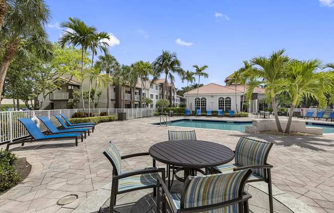 a patio with a table and chairs next to a swimming pool