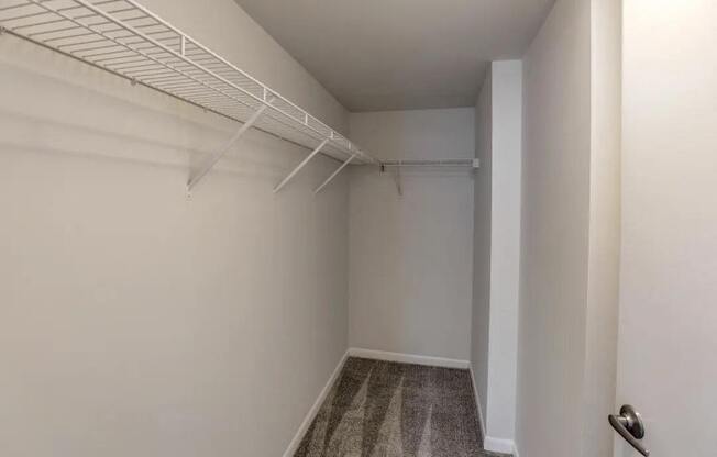 a walk in closet in an empty room with white walls and a white closet rack