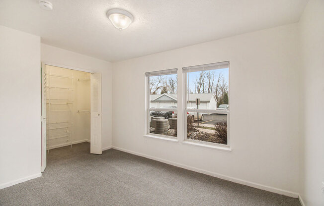 Bedroom with two large windows and a walk in closet at Canal 2 Apartments, Lansing, Michigan
