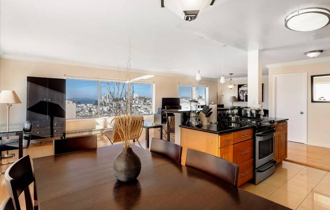 a kitchen and dining area with a wooden table and chairs and a large window with a city