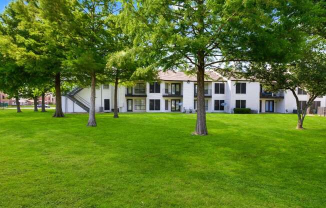 a grassy area with trees in front of a building