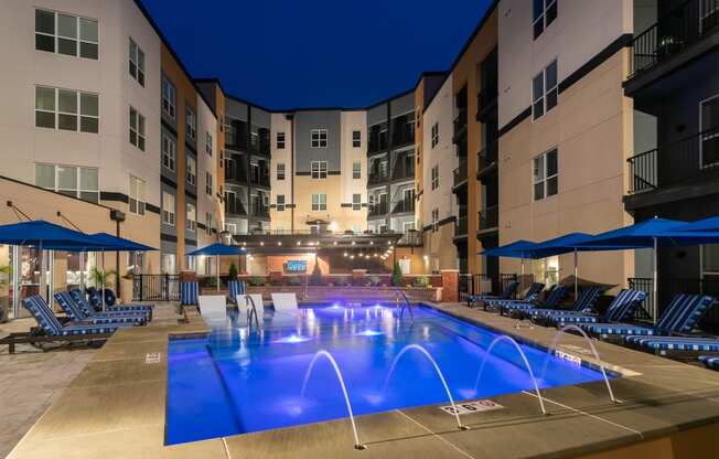 a large swimming pool in front of an apartment building at night at Aster Apartments, Beachwood, OH 44122