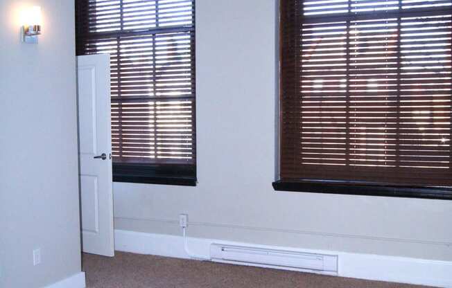 empty living room with two windows and a door at Residences at South High, Pittsburgh, PA 15203 ? 