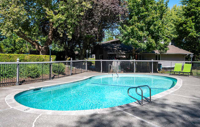 a pool with a fence around it and a house in the background