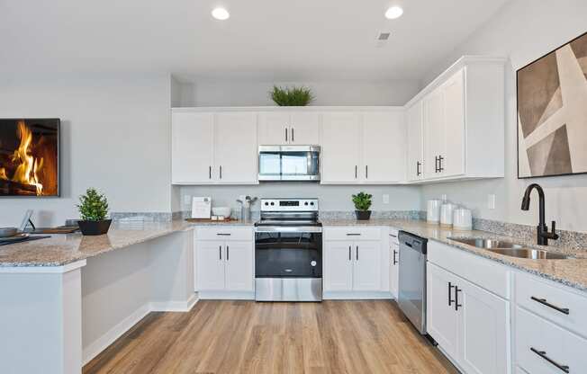 a new kitchen with white cabinets, wood-style floors, and granite countertops in a home at Sanctuary at Indian Creek