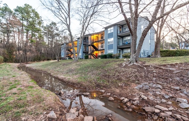 the stream in front of a house with a building in the background