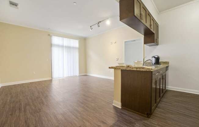 an empty living room with a kitchen and a window