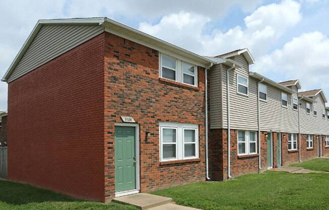 the front of a brick apartment building with a green door