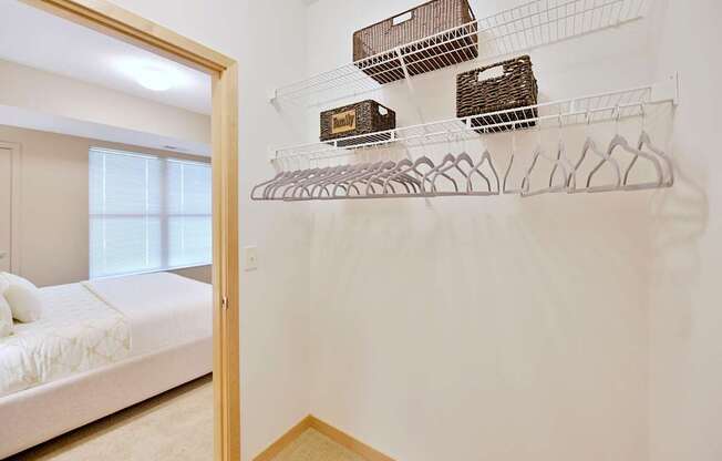 A white wall with wire shelves and baskets on it.