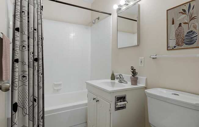 a bathroom with white fixtures and a black and white shower curtain