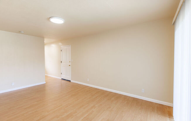 an empty living room with wood floors and a white door