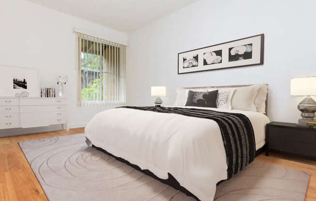 A bedroom with a large bed, a nightstand, and a dresser.