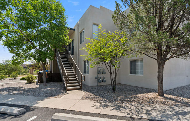 a white house with stairs and trees in front of it