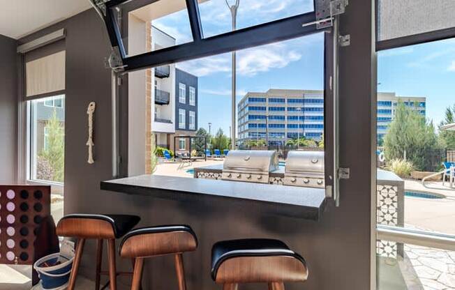 a bar with three stools in front of a large window