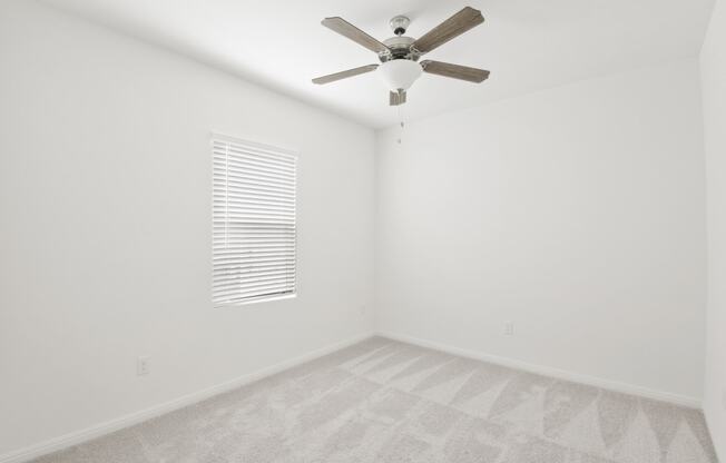 a bedroom with white walls and a ceiling fan