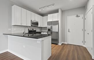 an empty kitchen with white cabinets and a black counter top
