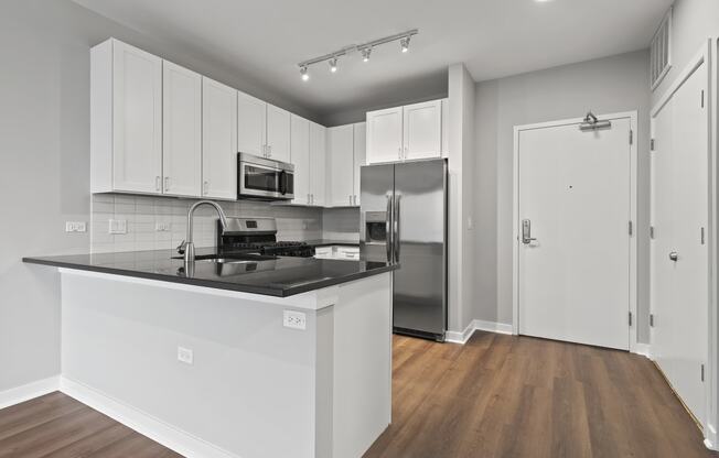 an empty kitchen with white cabinets and a black counter top