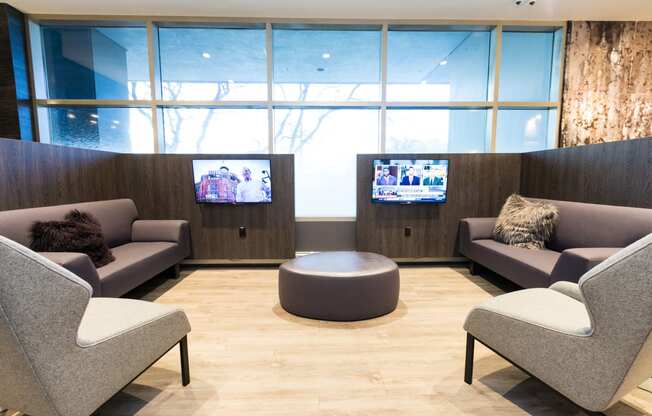 a waiting room with couches and chairs and two televisions at Apartments at Denver Place, Denver