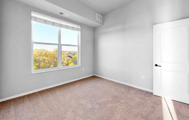 A room with a large window and a carpeted floor.