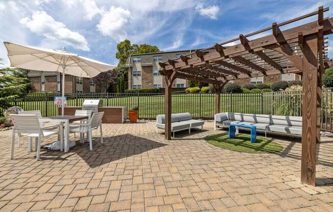 a brick patio with a pergola and tables and chairs