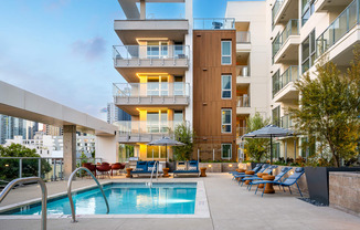 an outdoor swimming pool with chaise lounge chairs and sun umbrellas in front of an