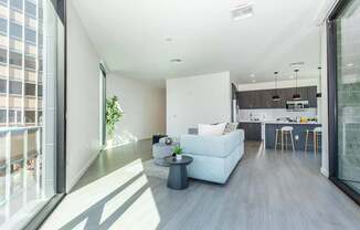 A modern living room with a white couch and a kitchen area in the background.