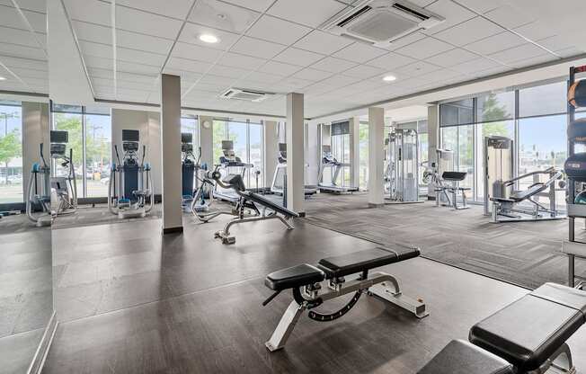 A gym with a variety of equipment including treadmills, weights, and exercise machines.