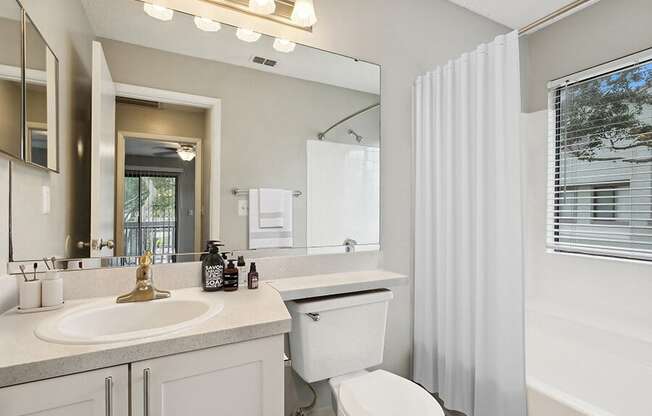 Model Bathroom with White Cabinets, Wood-Style Flooring & Shower/Tub at Huntington Place Apartments located in Sarasota, FL.